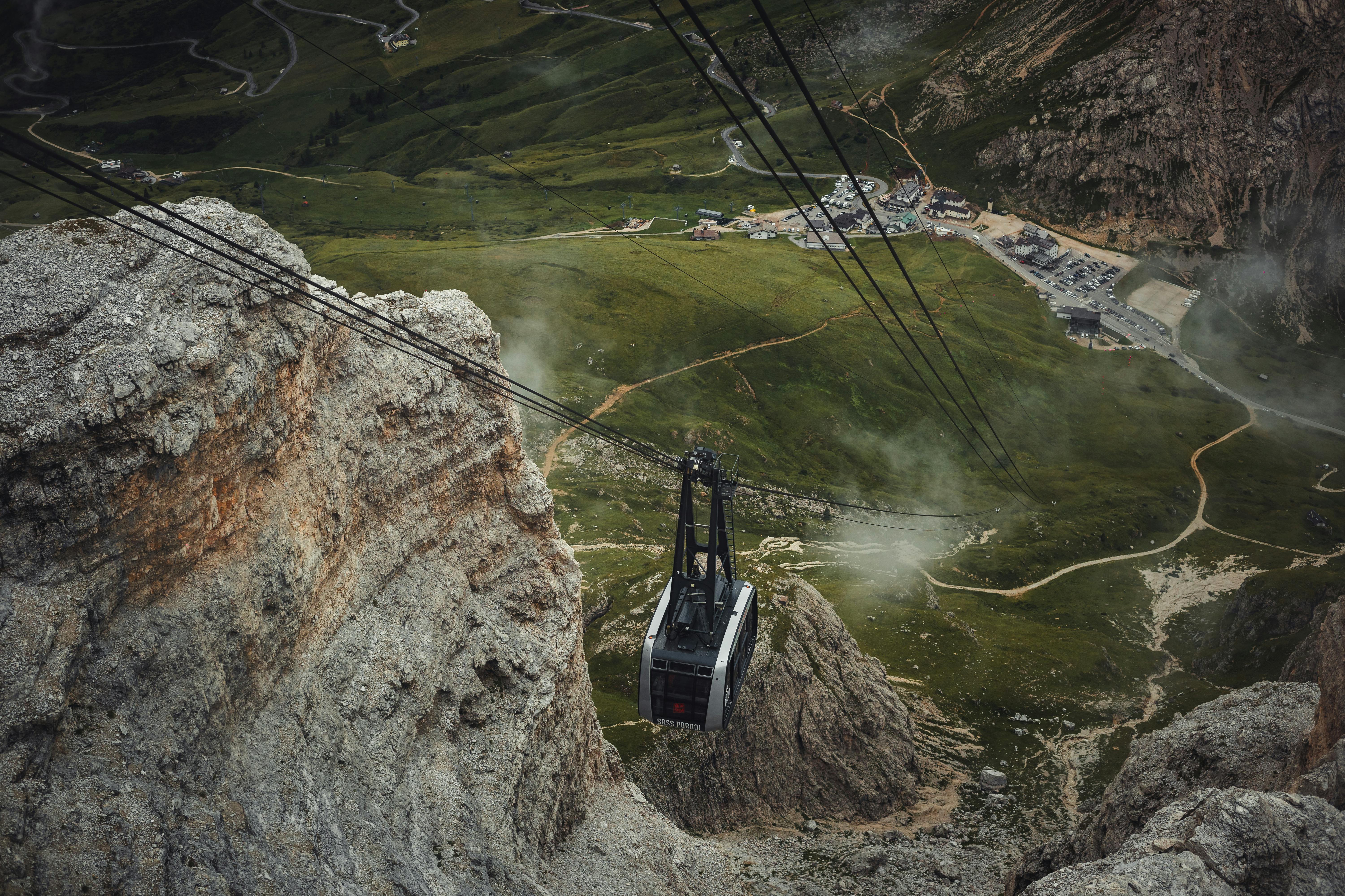 Aerial view of a cable car gliding over rocky mountains in summer.