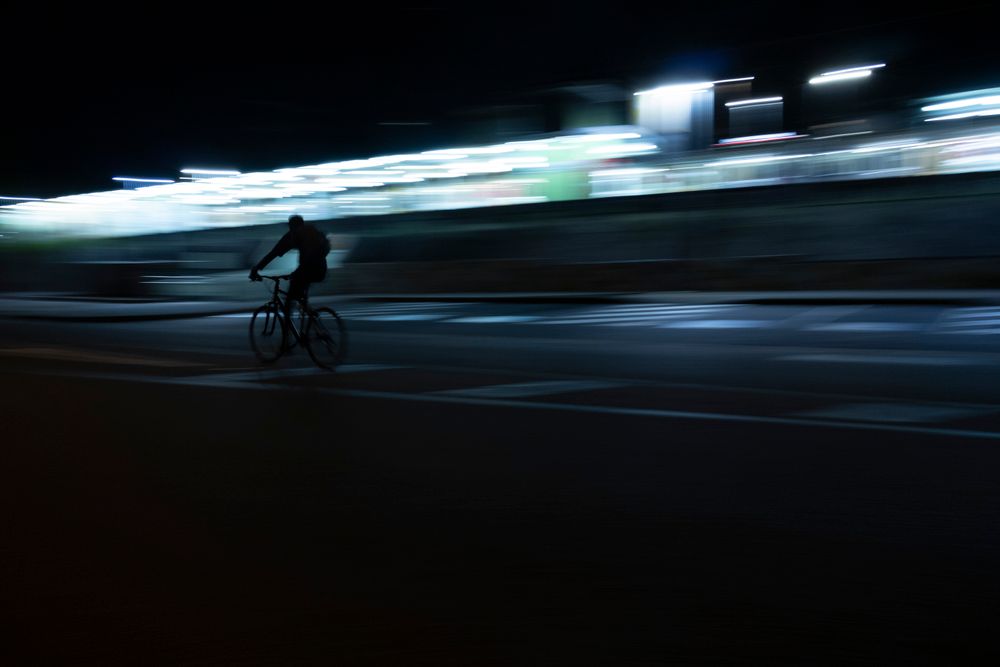 Radfahrer bei Nacht mit Lichtspuren durch Langzeitbelichtung