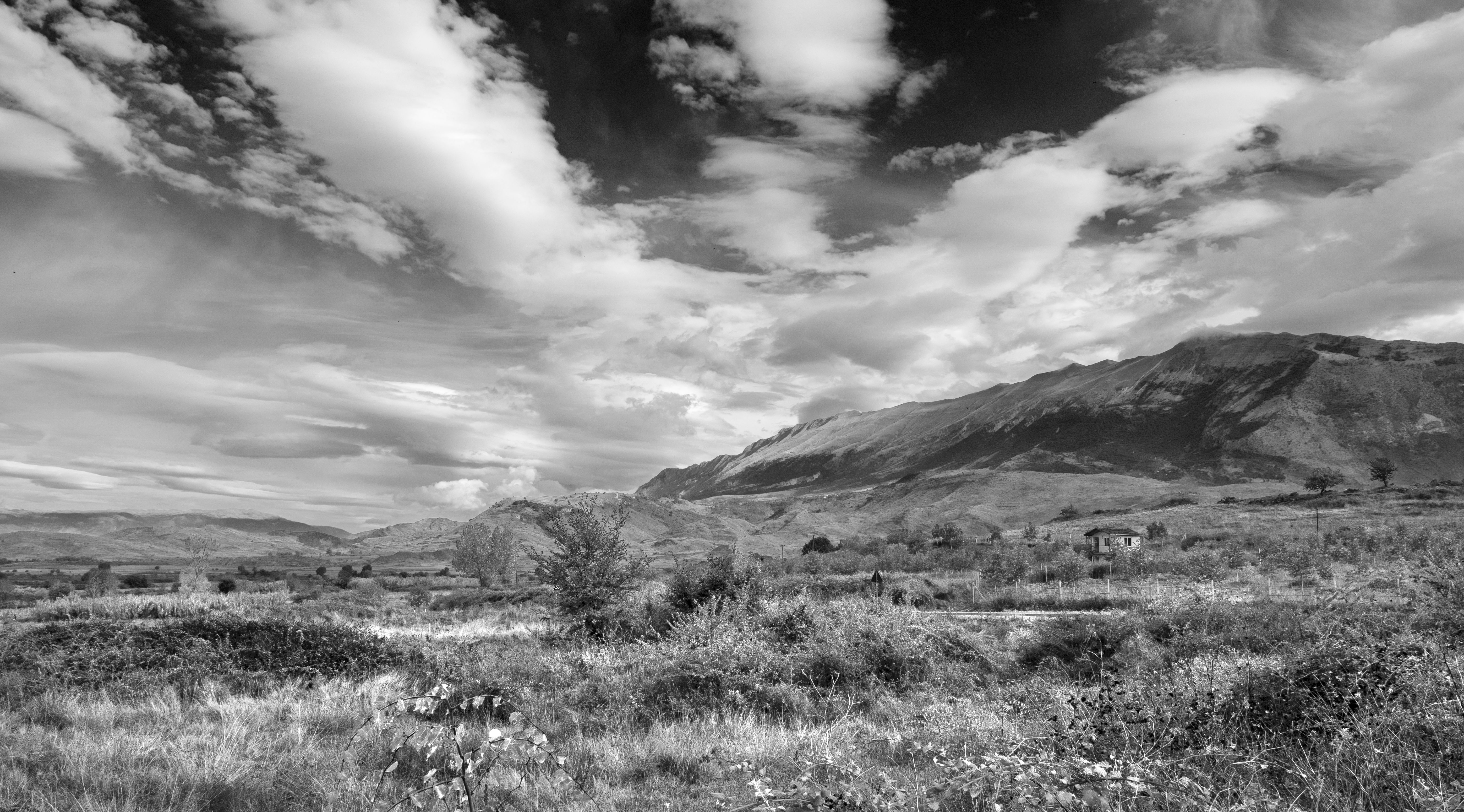 Breathtaking view of Albania's serene countryside, showcasing dramatic clouds and rugged terrain.
