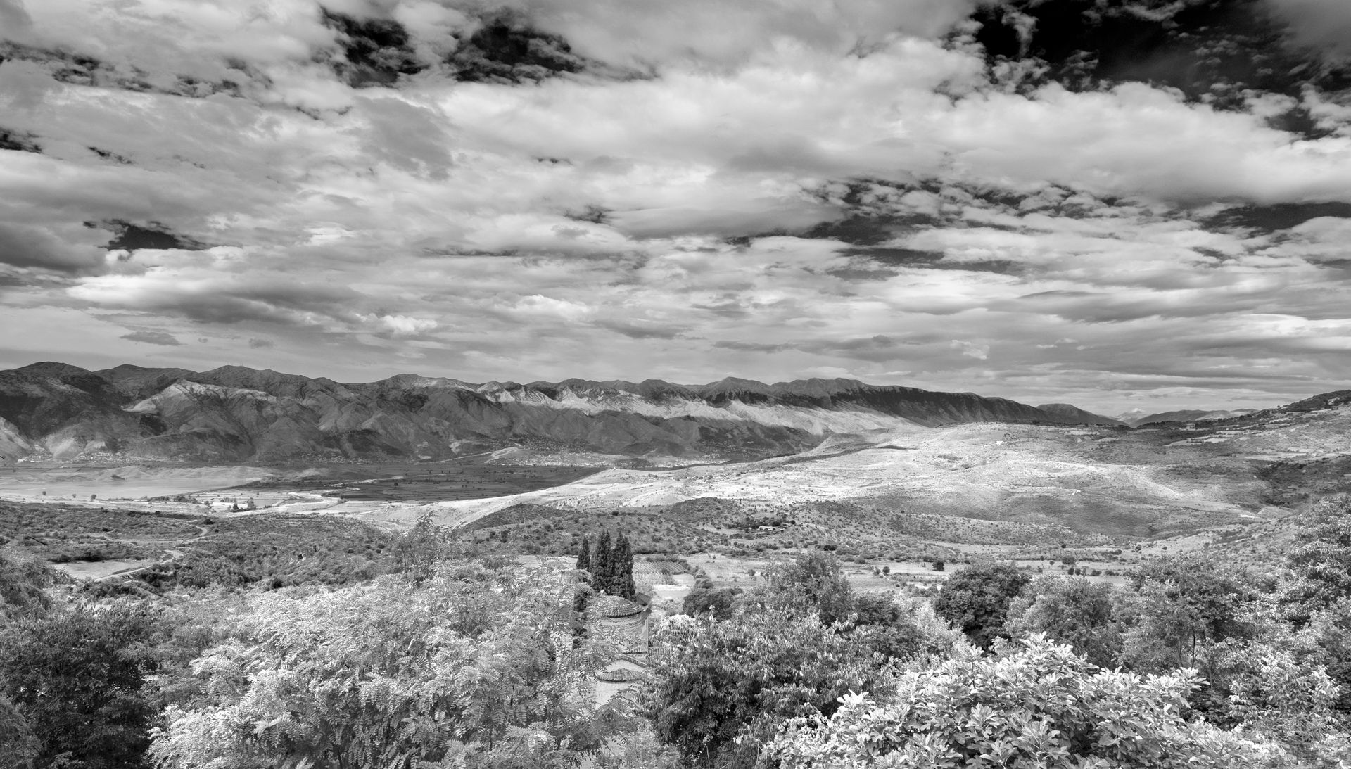 Dramatic black and white view of the Albanian countryside with mountains and cloudy skies.