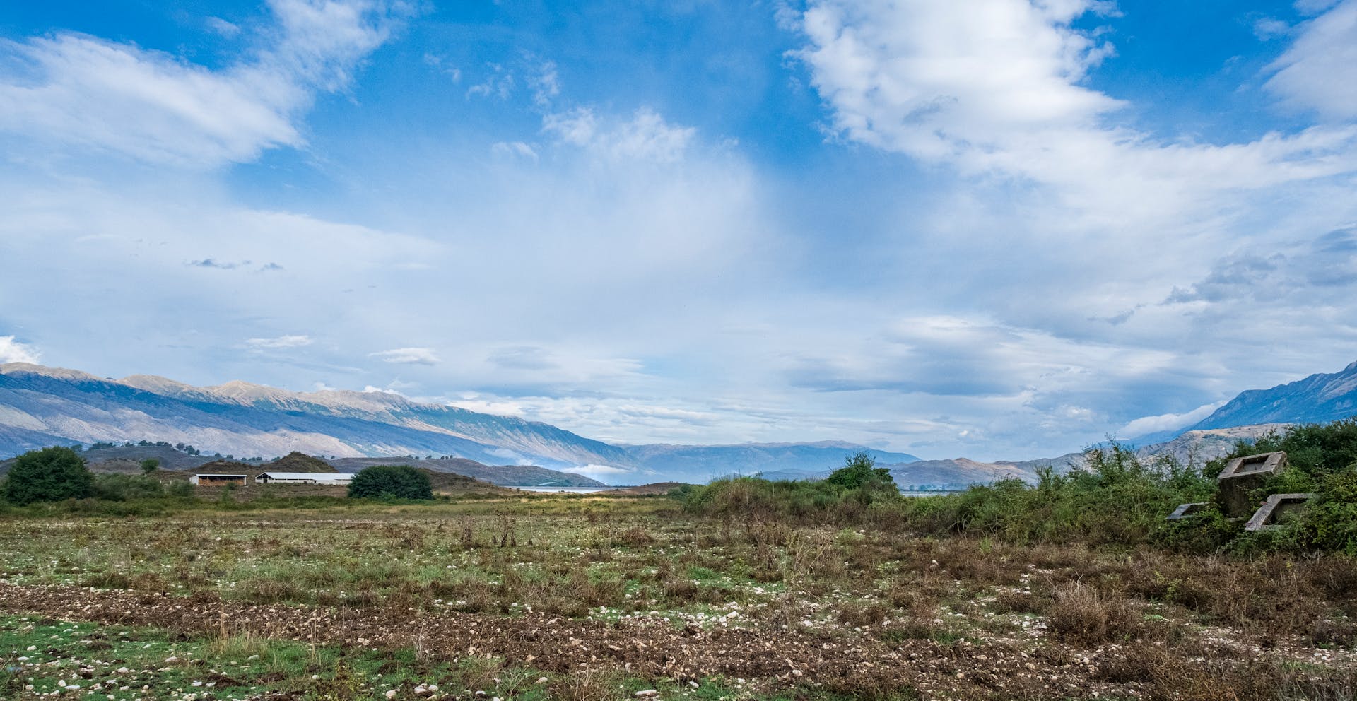 Expansive landscape view showcasing the beautiful Albanian countryside with majestic mountains under a blue sky.