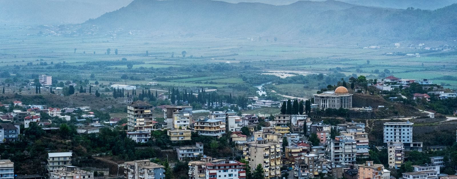 Vibrant cityscape of Albania with lush greenery and mountainous backdrop.