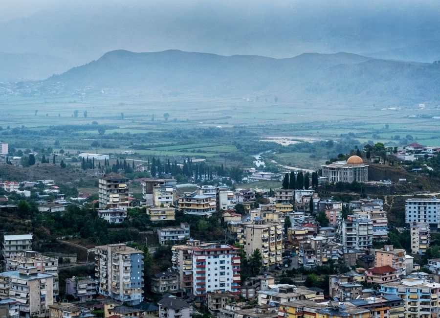 Vibrant cityscape of Albania with lush greenery and mountainous backdrop.
