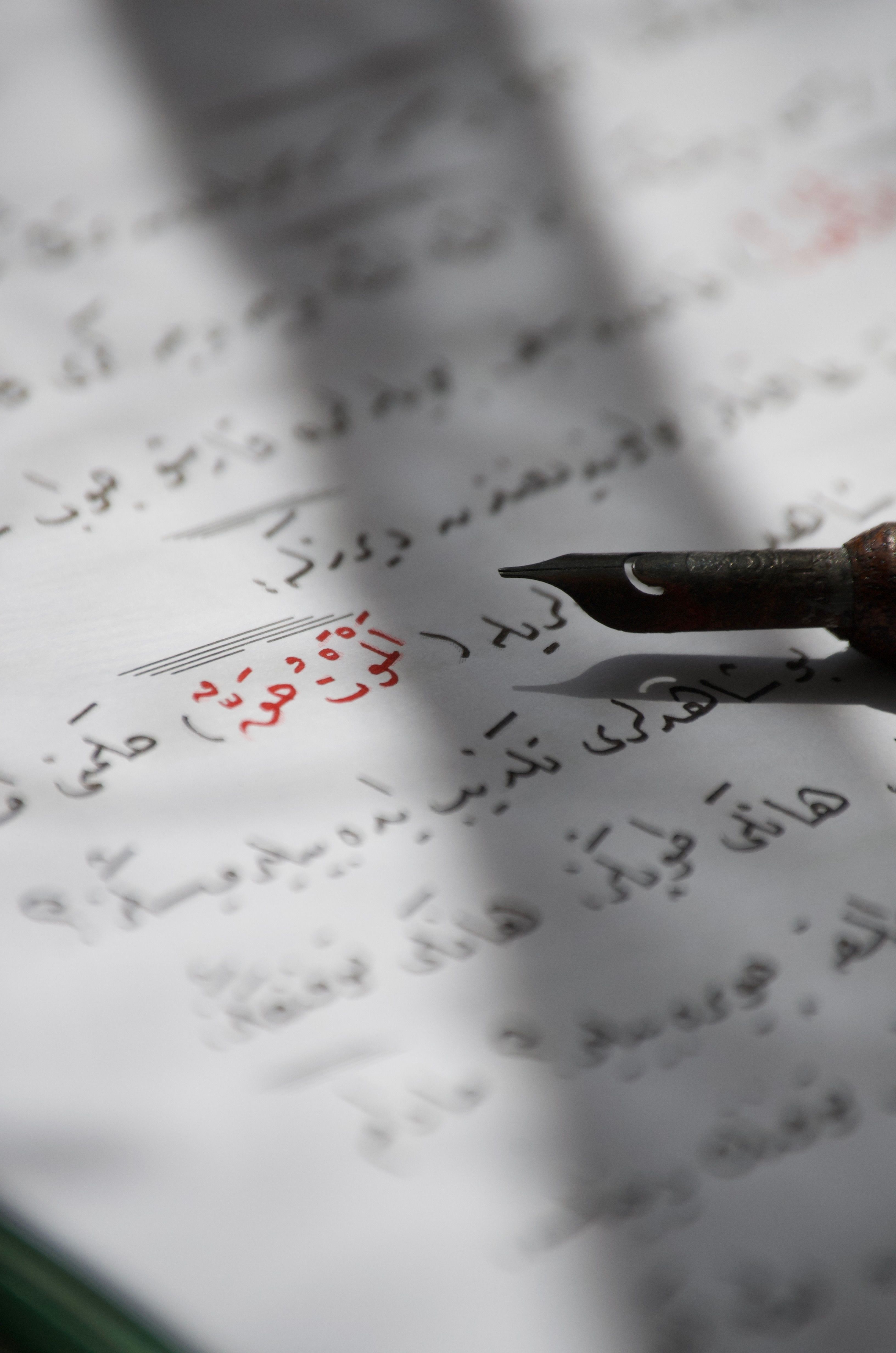 Close-up of an antique pen on an Arabic script page, highlighting the art of calligraphy.