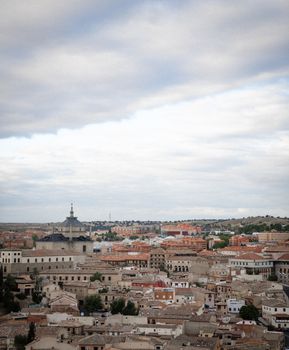 Expansive aerial view of the historic city of Toledo, Spain under a dramatic sky.