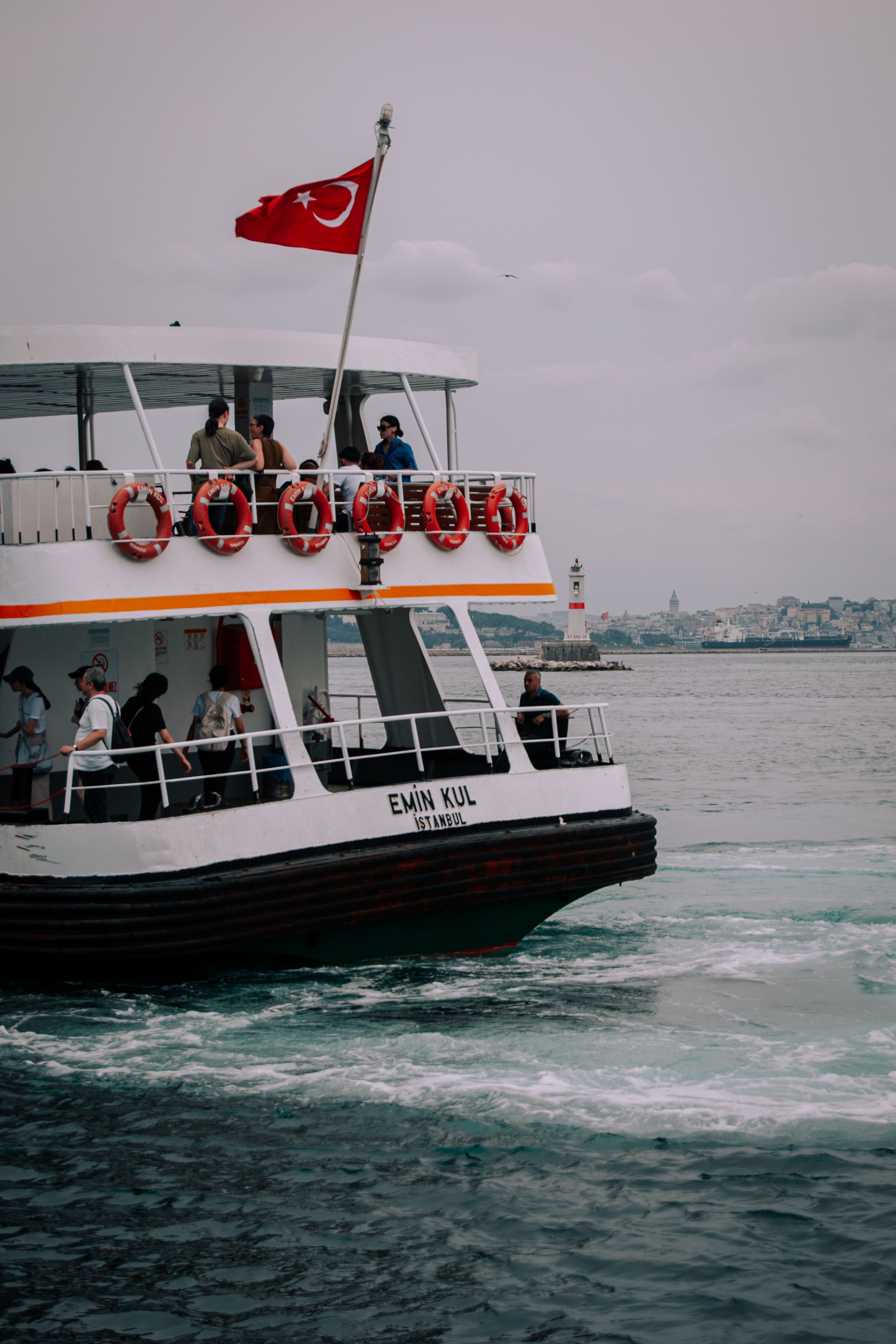A passenger ferry sails on the Bosphorus with a Turkish flag flying, offering stunning views of Istanbul.