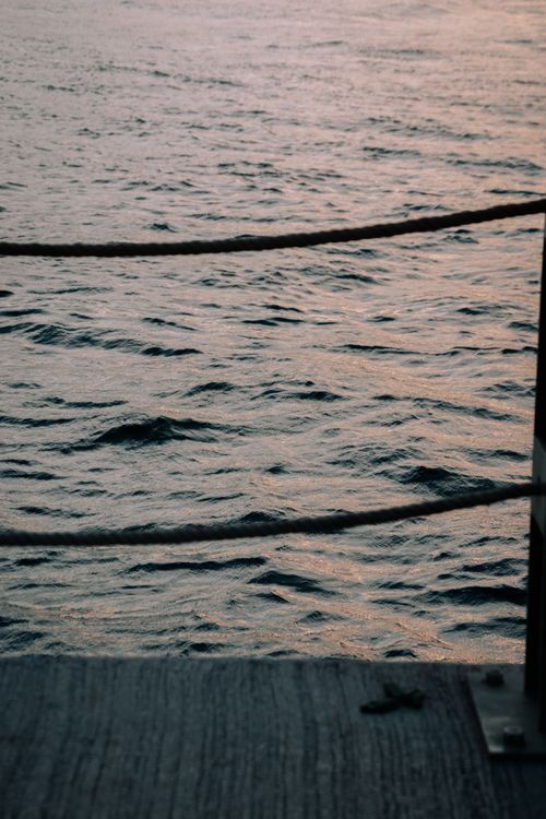 Free A tranquil view of ocean waves from a pier during sunset, evoking calmness. Stock Photo