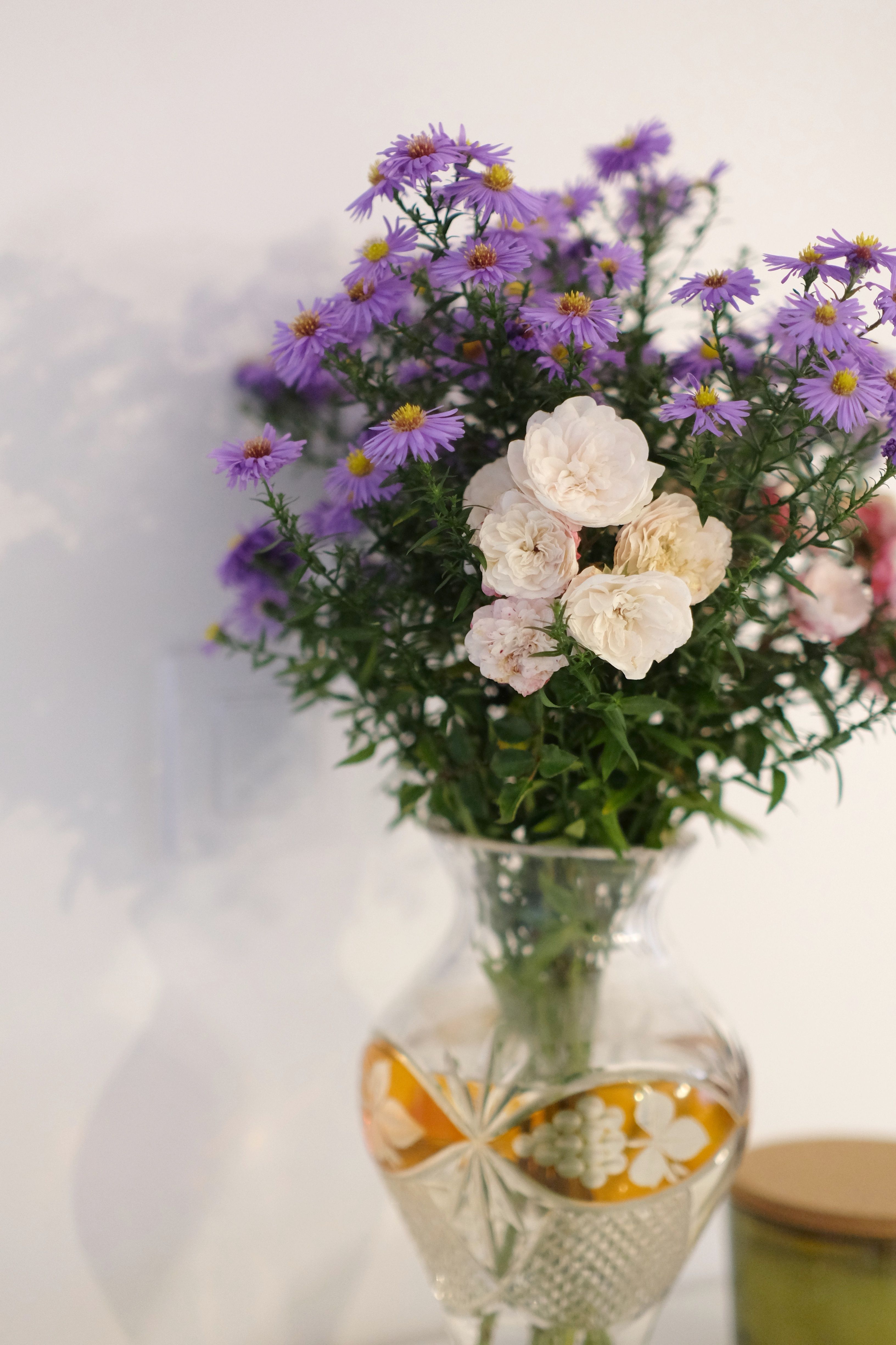 [ColoSach]-beautiful-bouquet-of-purple-asters-and-roses-in-a-decorative-glass-vase-on-a-bright-background.
