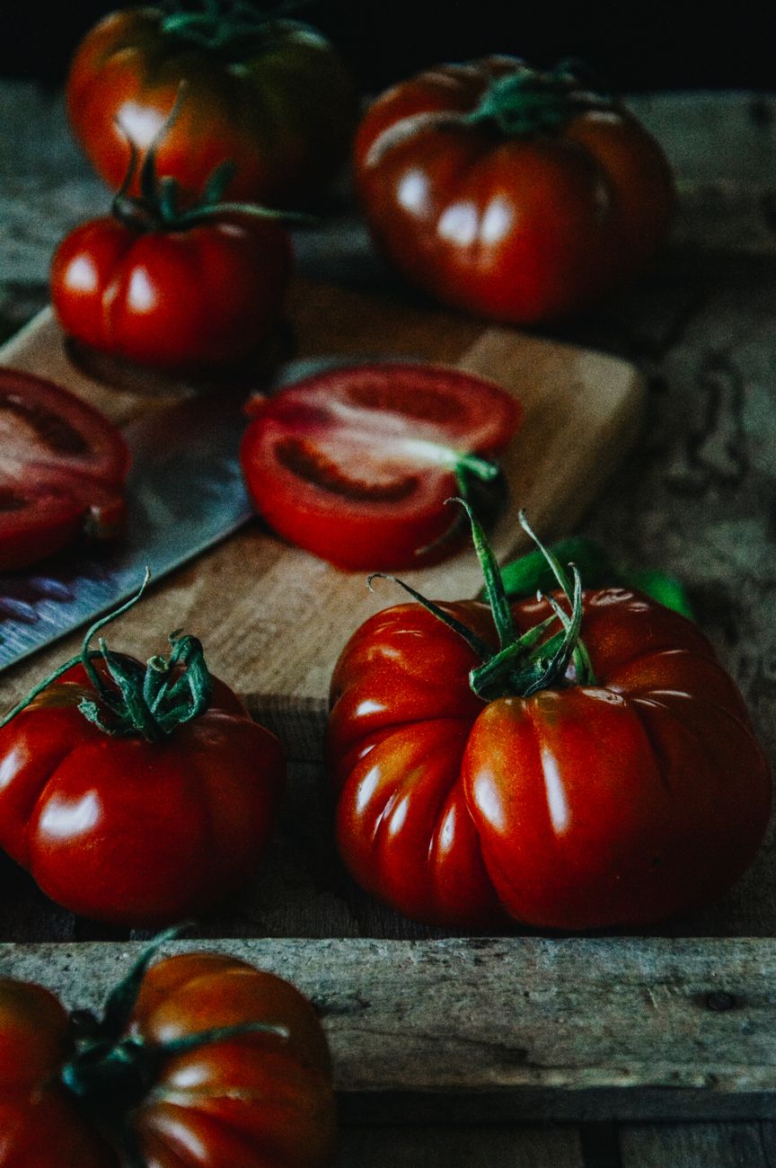 Mixed heirloom tomatoes on a wooden table showing different shapes and colours