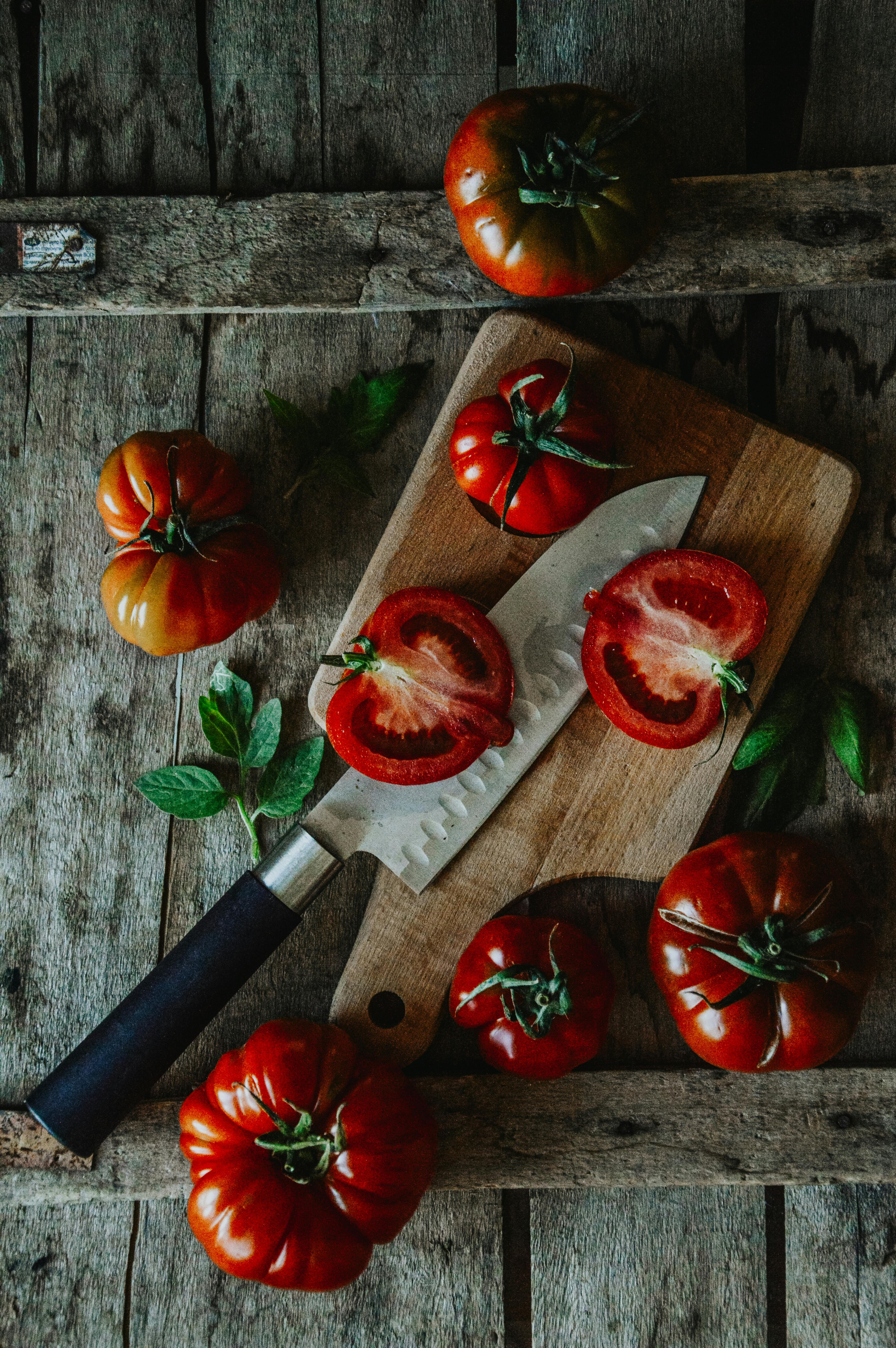 Heirloom tomatoes beside a knife on a worn kitchen board
