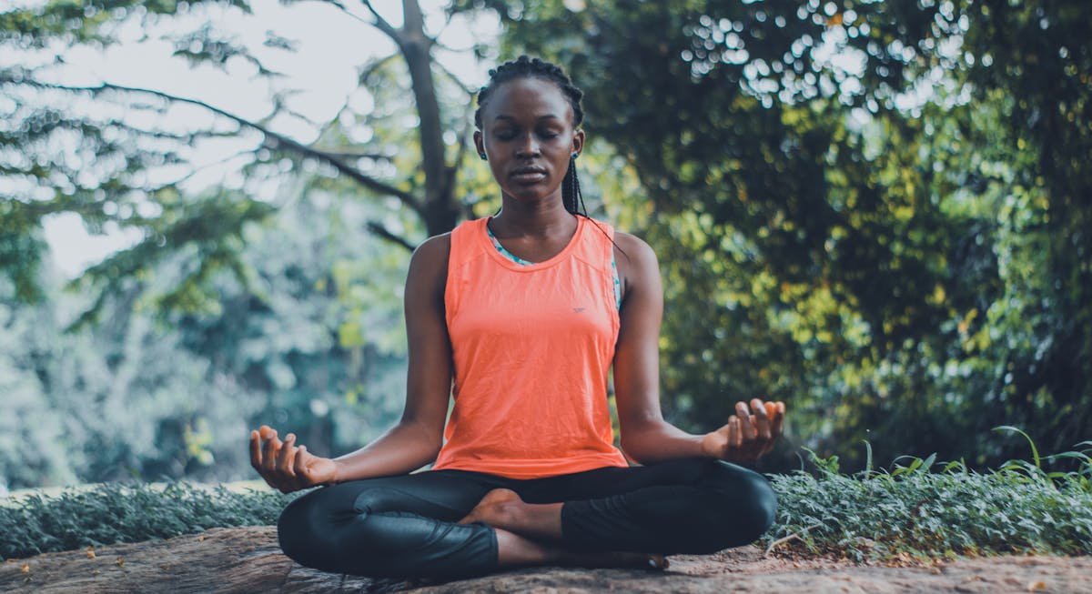 Person meditating outdoors in peaceful natural setting