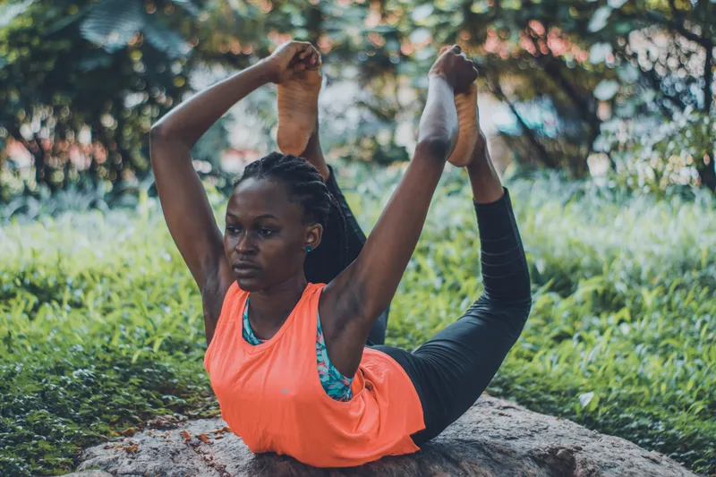 A woman holding a slow, open stretch outdoors in the sun