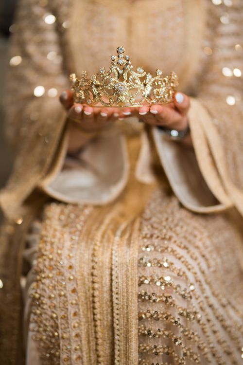 Free A detailed close-up of a golden tiara held by a woman in an ornate dress, exuding luxury and royalty. Stock Photo