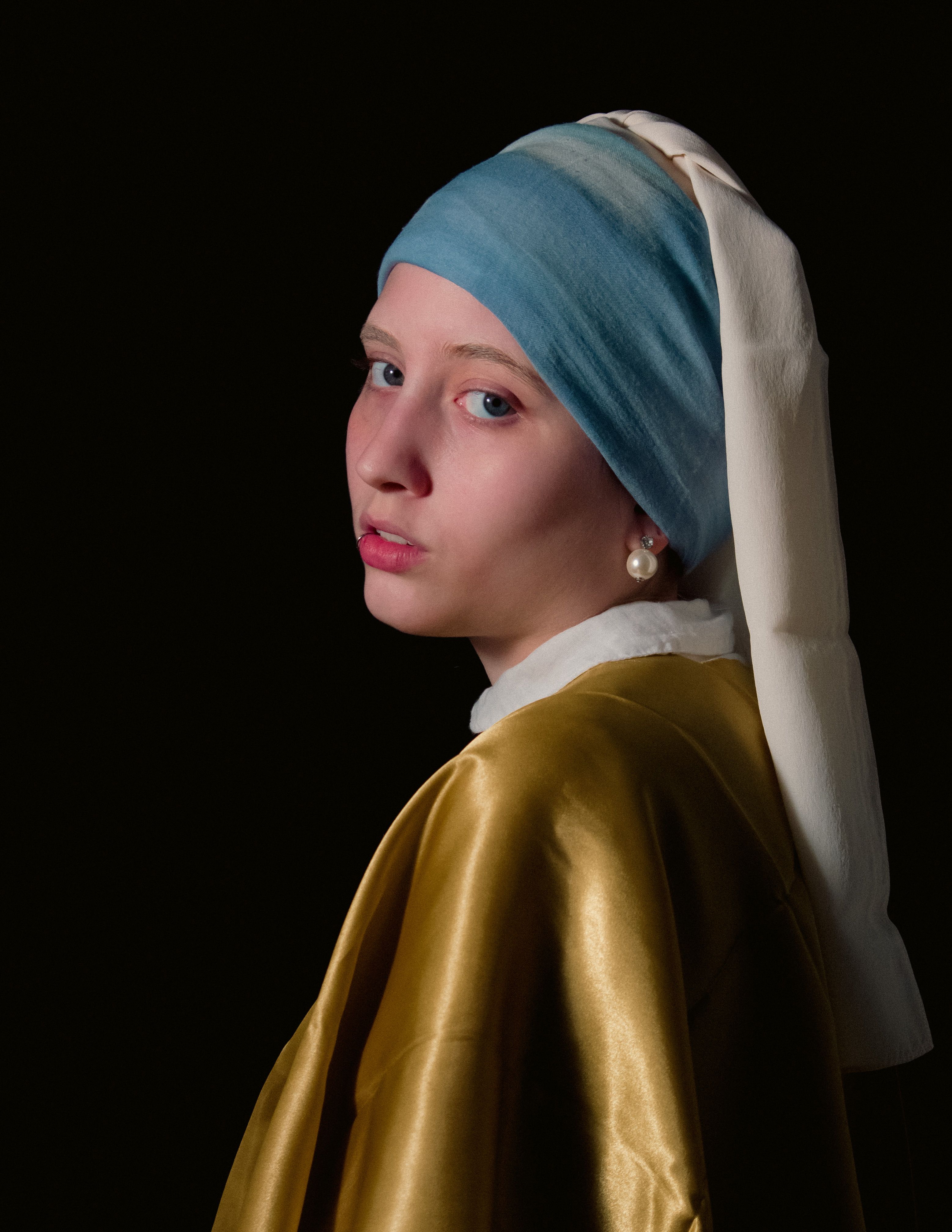 Classic portrait with a dark backdrop capturing a woman in a blue headscarf and gold cloak, echoing historical art.