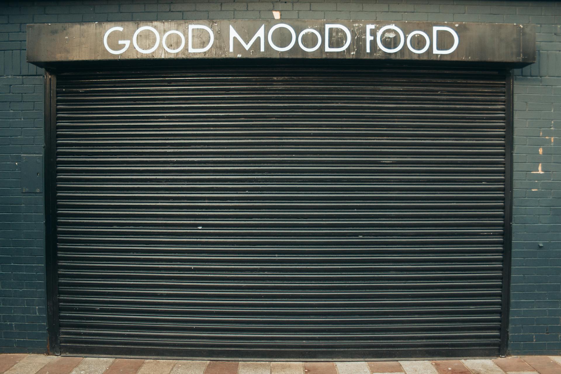Closed metal shutter with 'Good Mood Food' sign, conveying restaurant closure or urban elements.