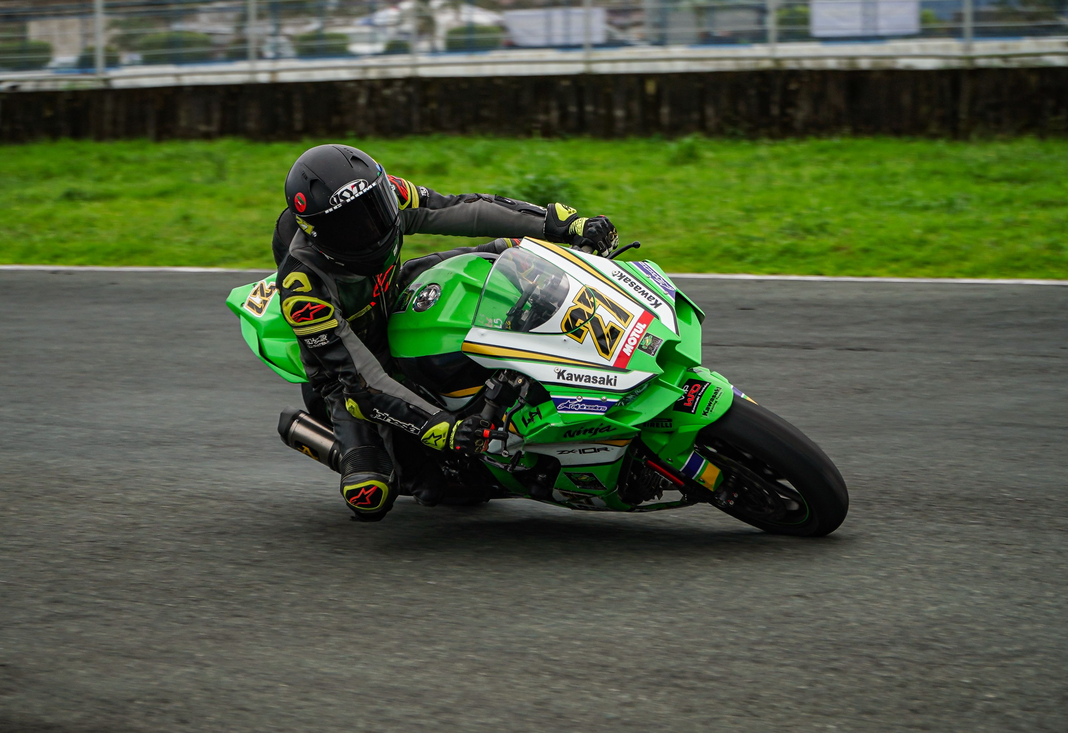 Motorcyclist racing at high speed on a track, showcasing agility and precision on a green Kawasaki bike.