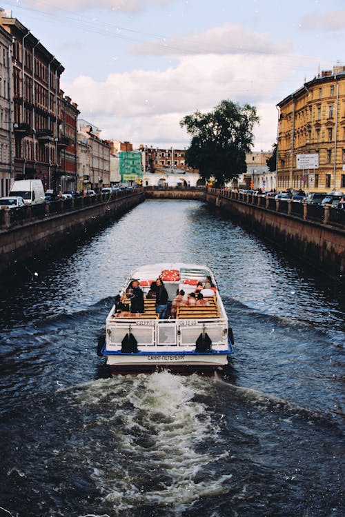 免费 白色和蓝色的小船，在城市河上的照片 素材图片
