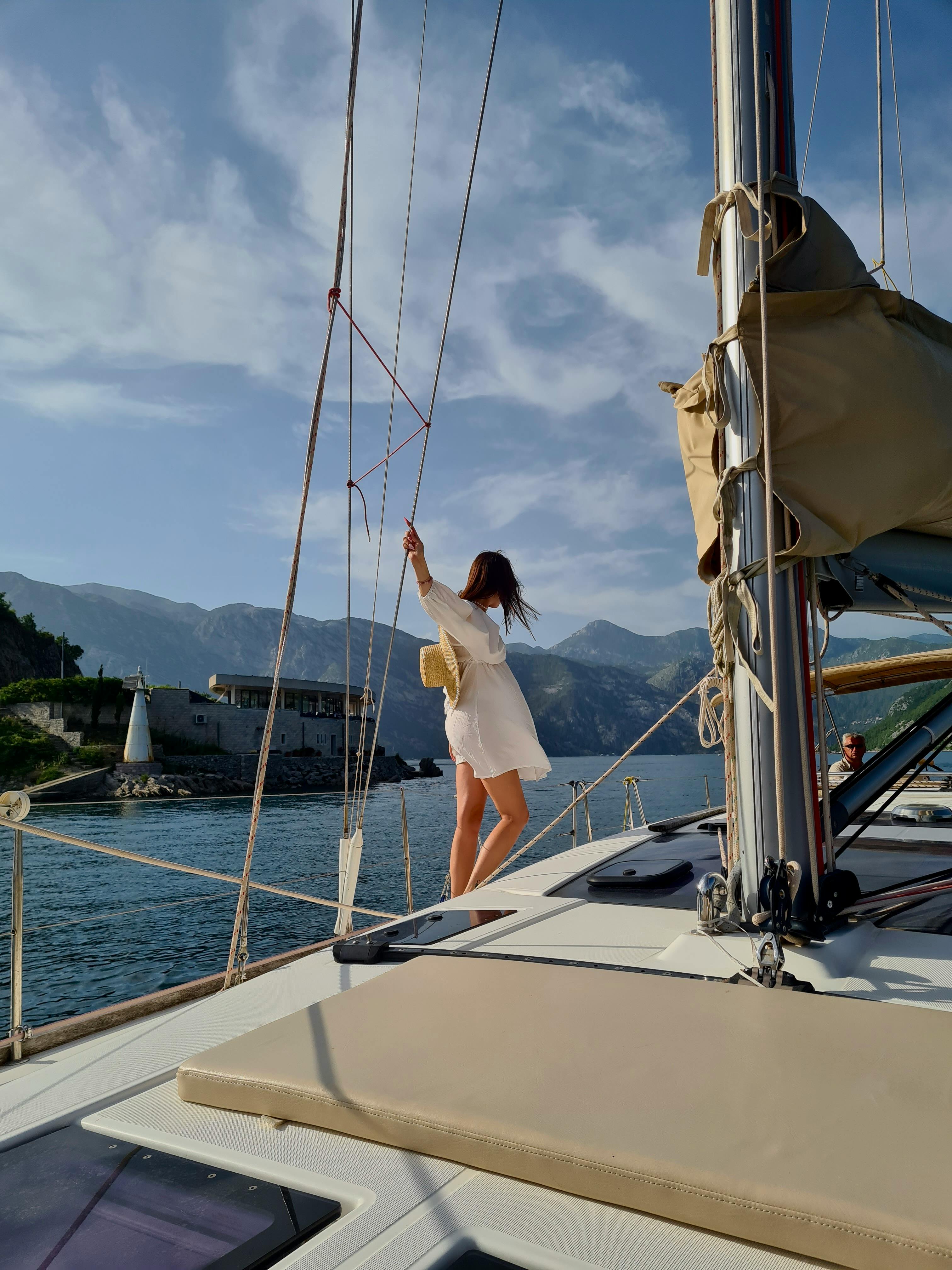 A woman relaxes on a yacht with scenic Montenegro views, enhancing travel vibes.
