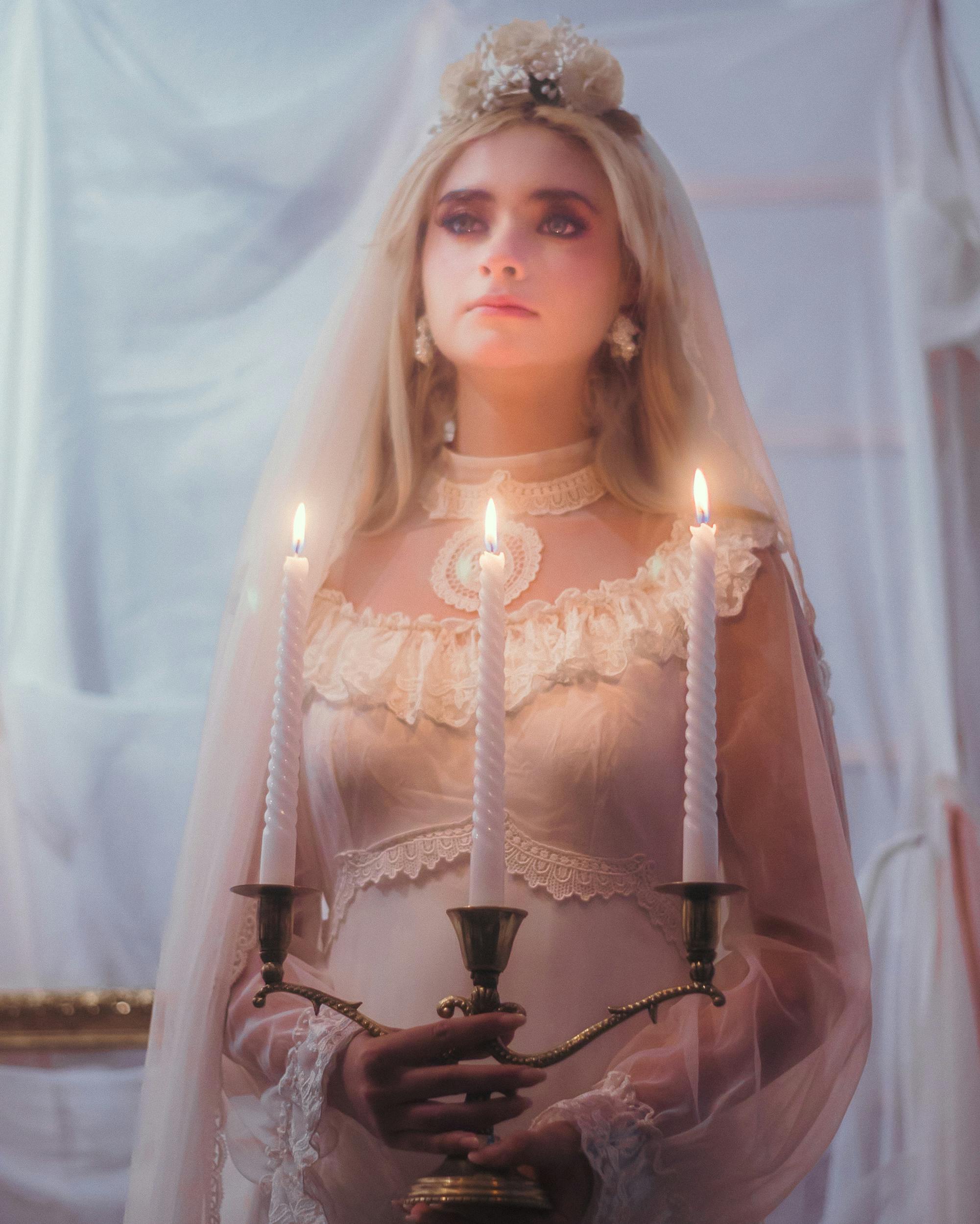 Ethereal bride in vintage dress holding a candelabra, creating a mysterious Halloween vibe.