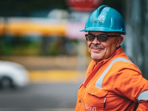 Free Portrait of a smiling construction worker with a blue helmet and orange uniform in San José. Stock Photo