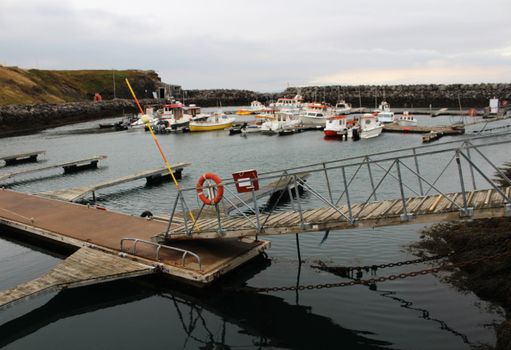 Scenic Iceland marina with boats docked against a rocky shoreline and calm waters.