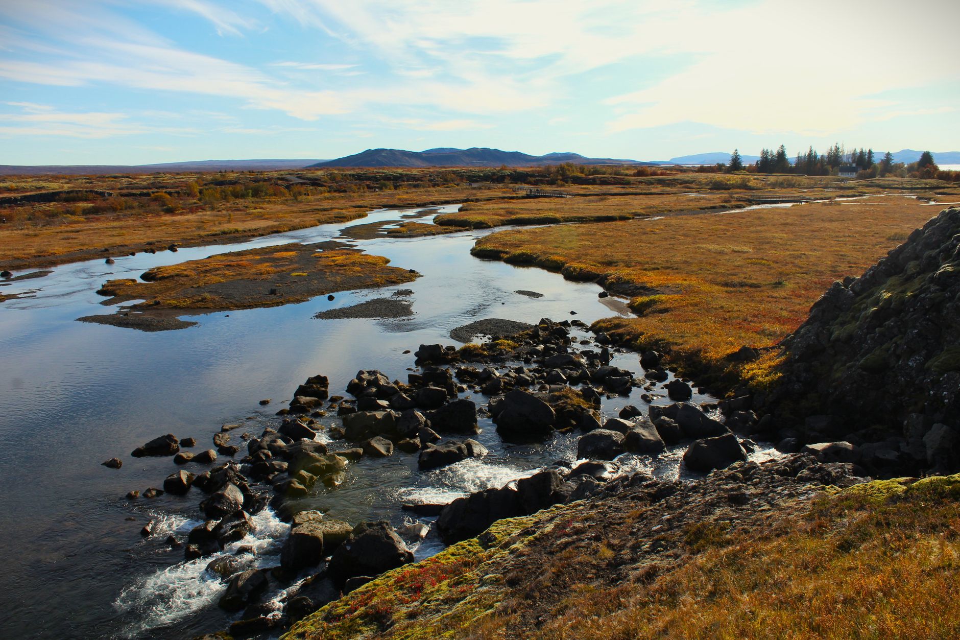 Breathtaking view of Icelandic river meandering through autumn foliage with mountains in the distance.