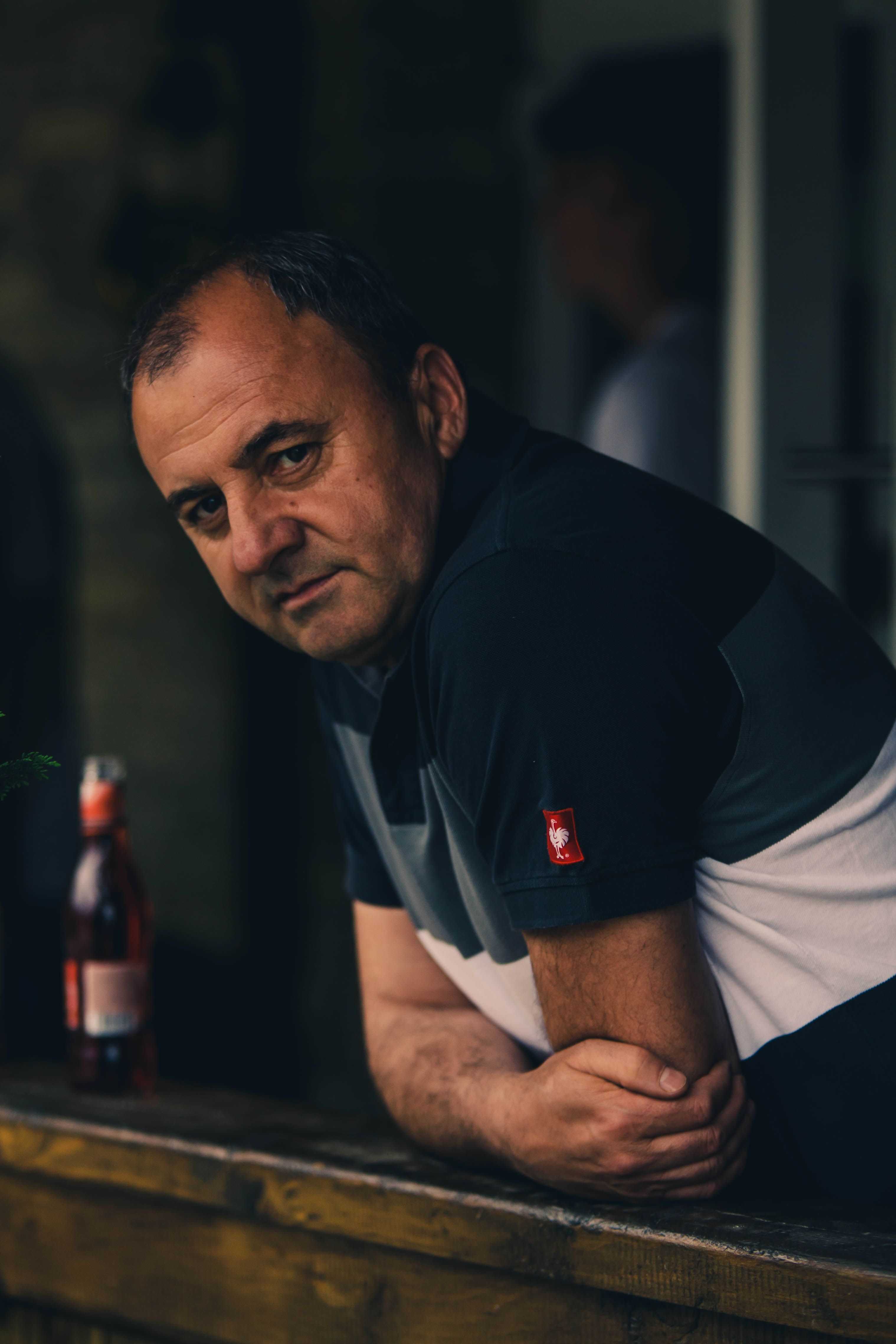 A contemplative adult man leaning on a balcony railing with a moody atmosphere.