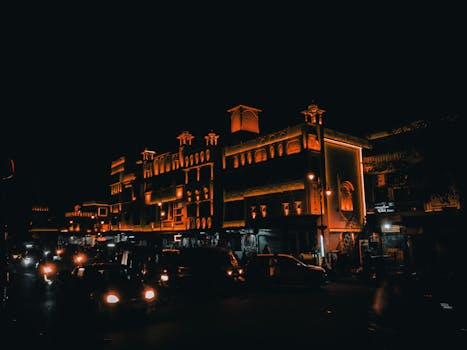Orange-lit buildings and bustling street traffic form a cinematic night view in India.