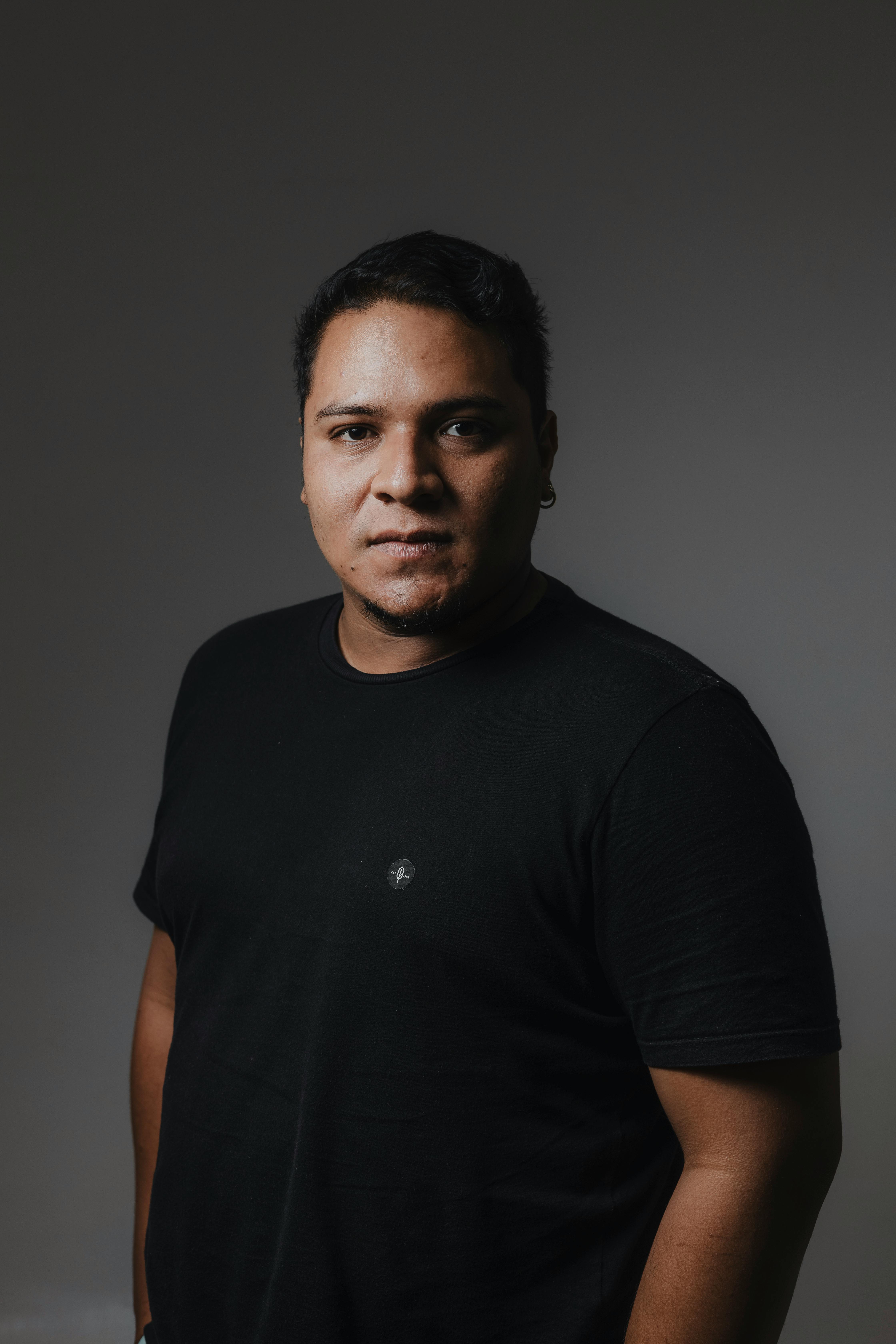 Studio portrait of an adult man in a black t-shirt with a neutral background.