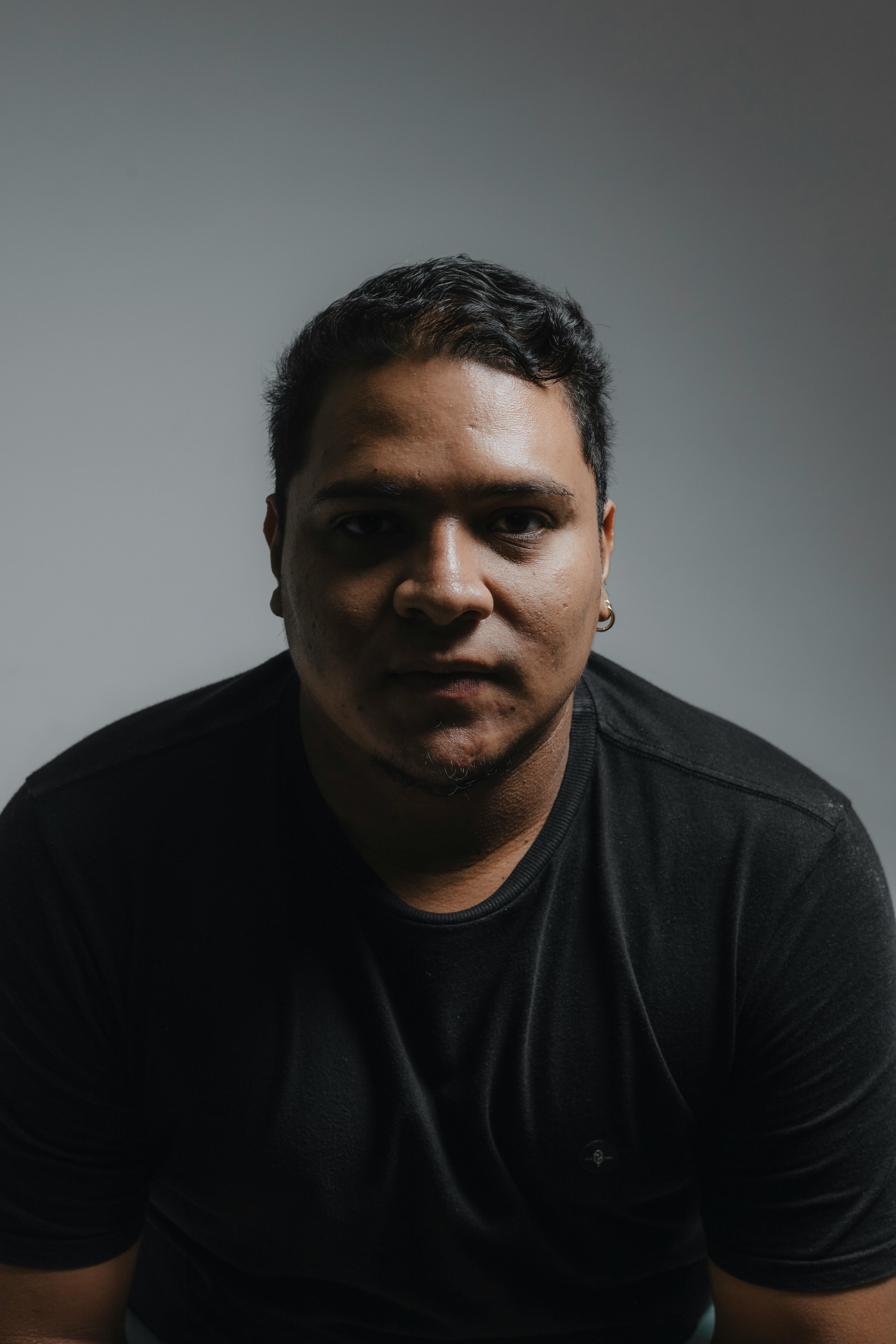 Dramatic portrait of a man in a studio setting with moody lighting.