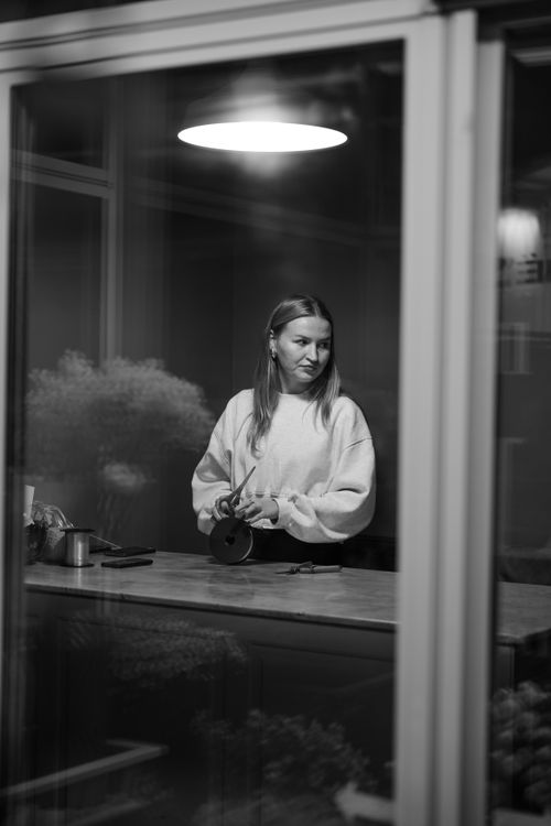 Free A stylish woman stands indoors, captured in a sophisticated black and white portrait. Stock Photo