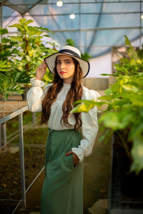 Free A stylish woman in a greenhouse surrounded by lush greenery and natural light. Stock Photo