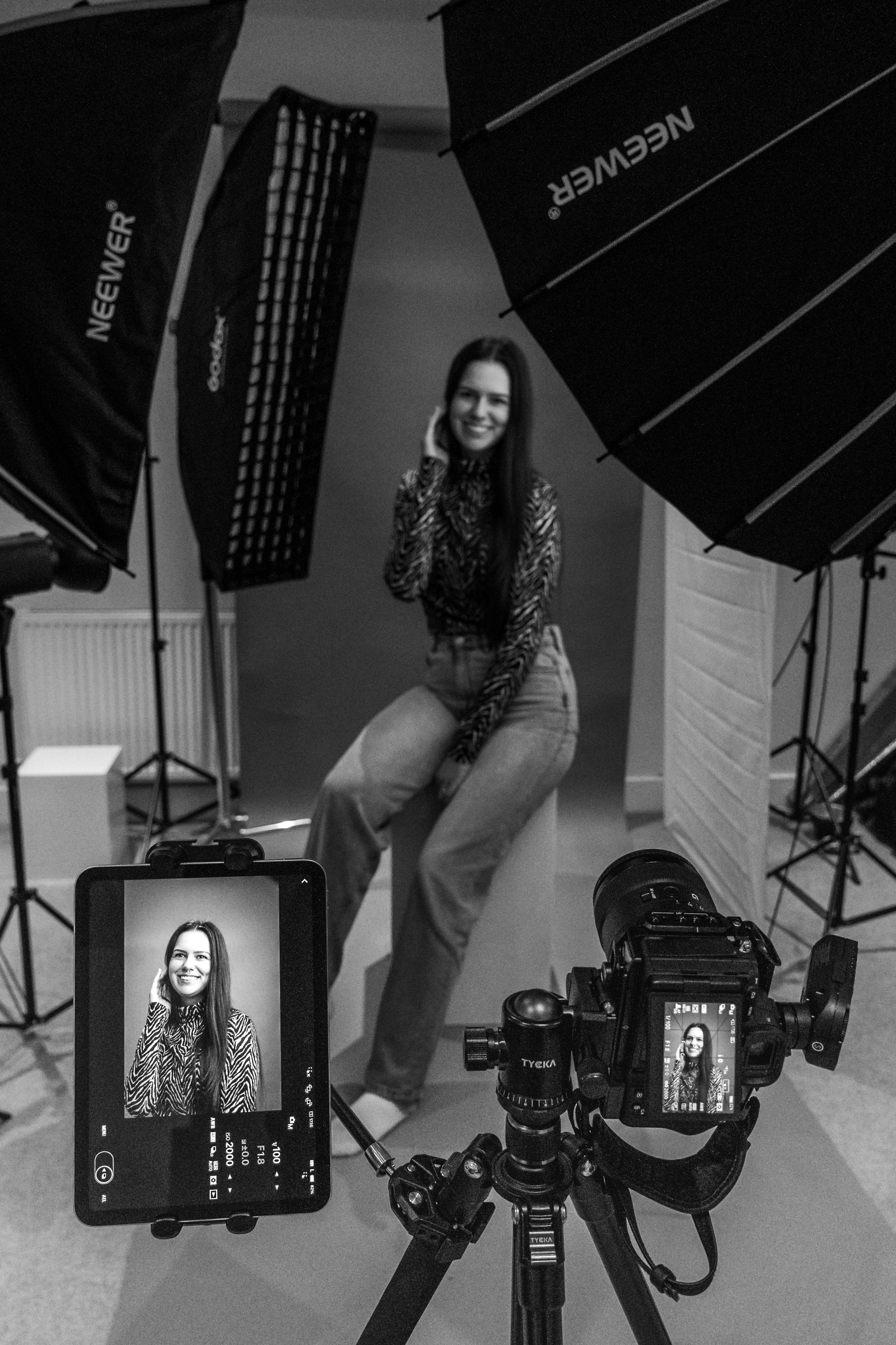 Black and white image of a woman during a photoshoot in a studio with equipment.