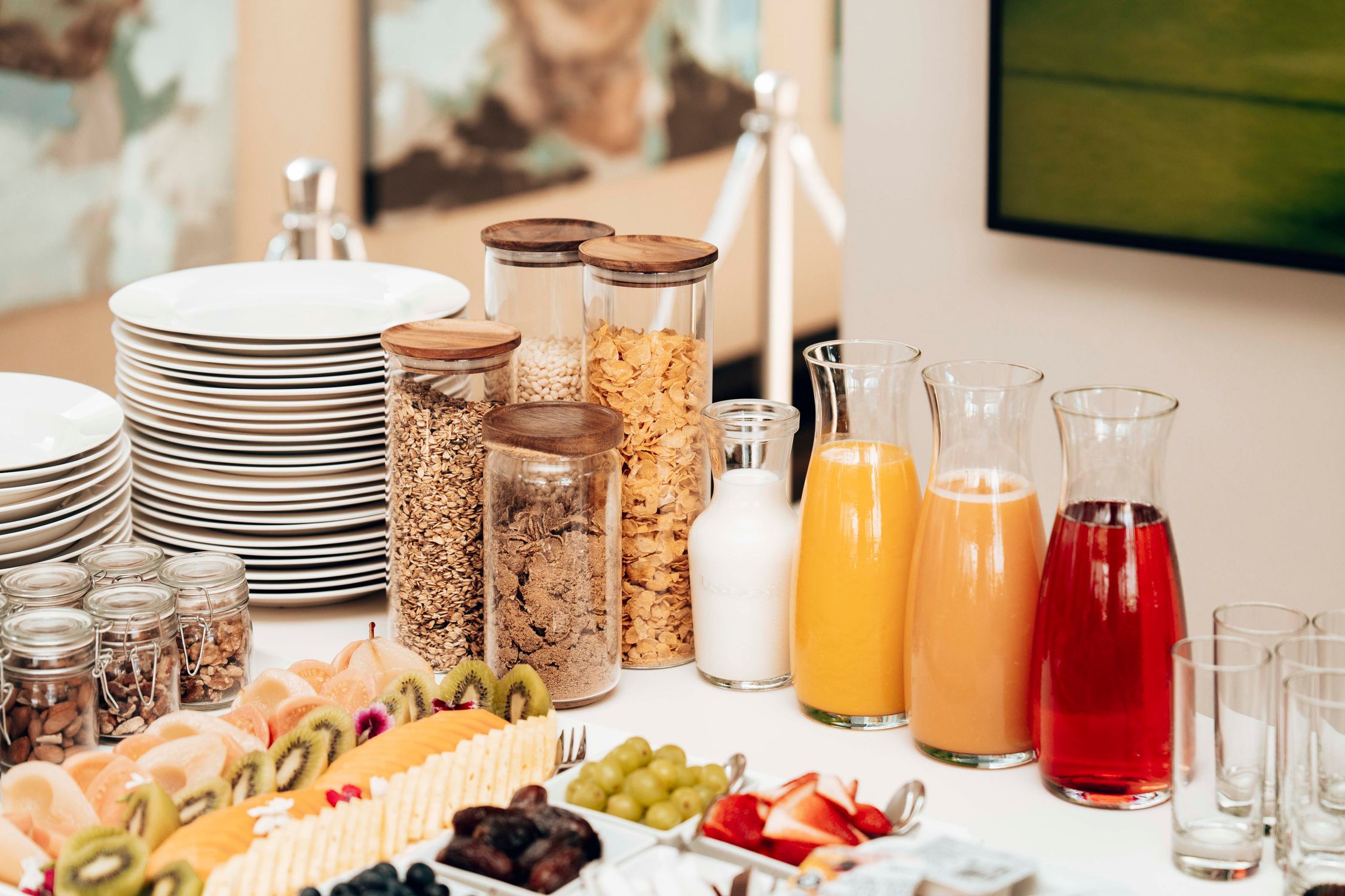 A variety of breakfast items including cereals, fresh fruits, and juices arranged on a buffet table.