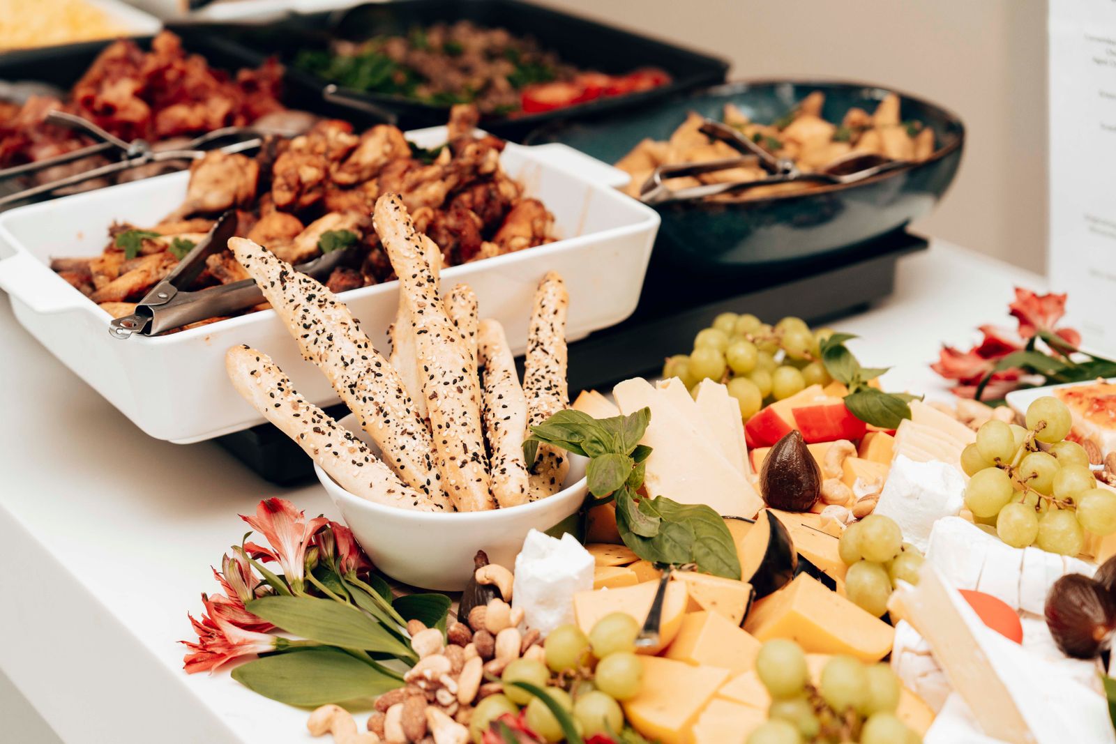 A mouth-watering assortment of cheeses, breadsticks, and fruits in a buffet setting. Perfect for catering events.