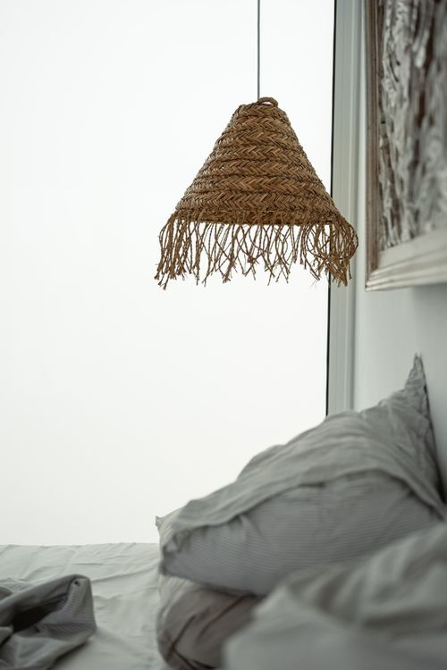 Free Stylish bedroom featuring a woven rattan lamp and gray bedding in Lanzarote. Stock Photo