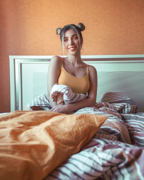 Free Photo of Smiling Woman in Orange Spaghetti Strap Top Sitting in Bed  Stock Photo