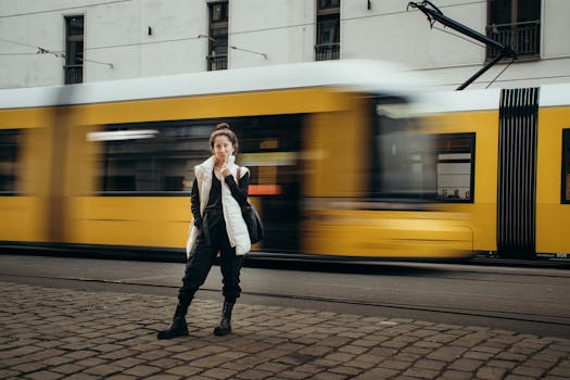 A stylish woman stands confidently as a tram rushes by in Berlin, Germany.