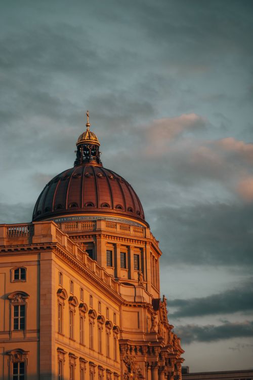 Free Stunning view of the Berlin Cathedral's dome lit by the warm sunset glow against a moody sky. Stock Photo
