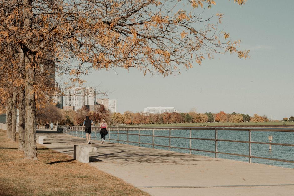 People jogging along the beautiful Milwaukee waterfront in autumn, framed by colorful fall foliage.