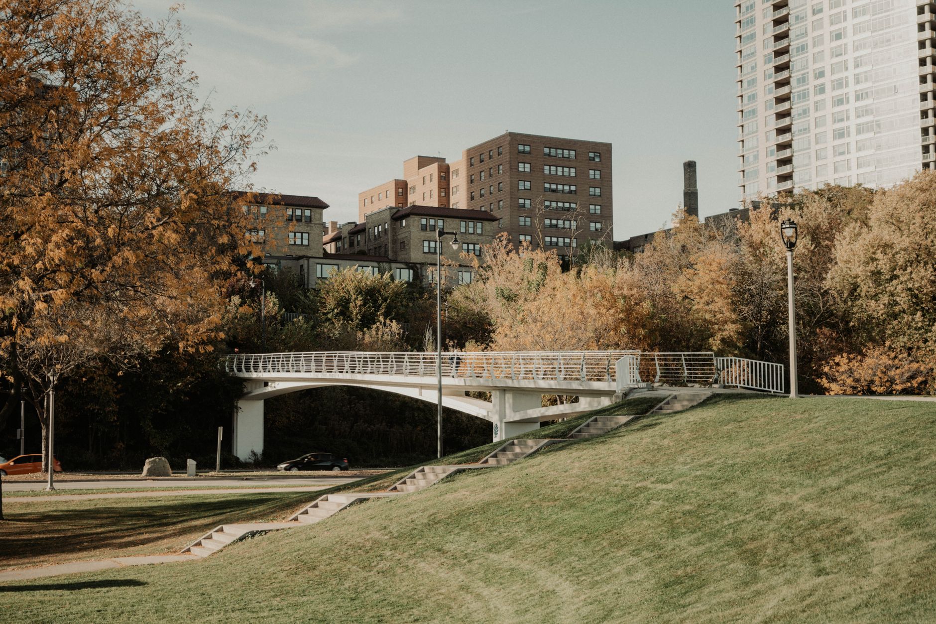 A serene autumn scene featuring a pedestrian bridge with downtown Milwaukee in the background.