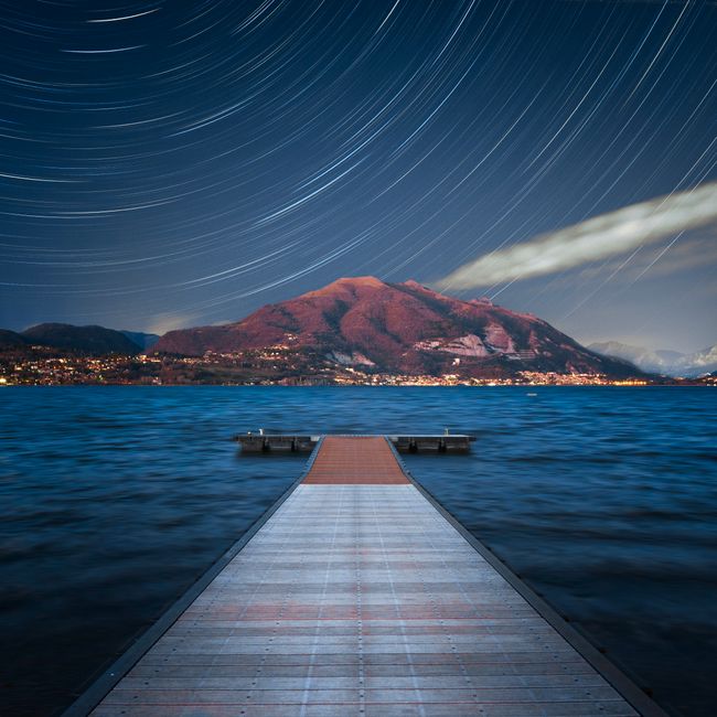 Gorgeous mountain and lake view under a star-filled sky in Lombardia, Italy.
