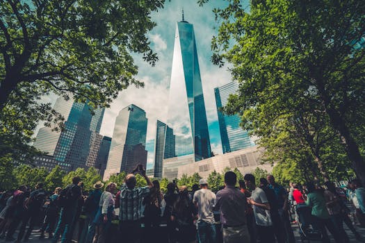Crowd at One World Trade Center, surrounded by greenery and urban skyscrapers in New York City.