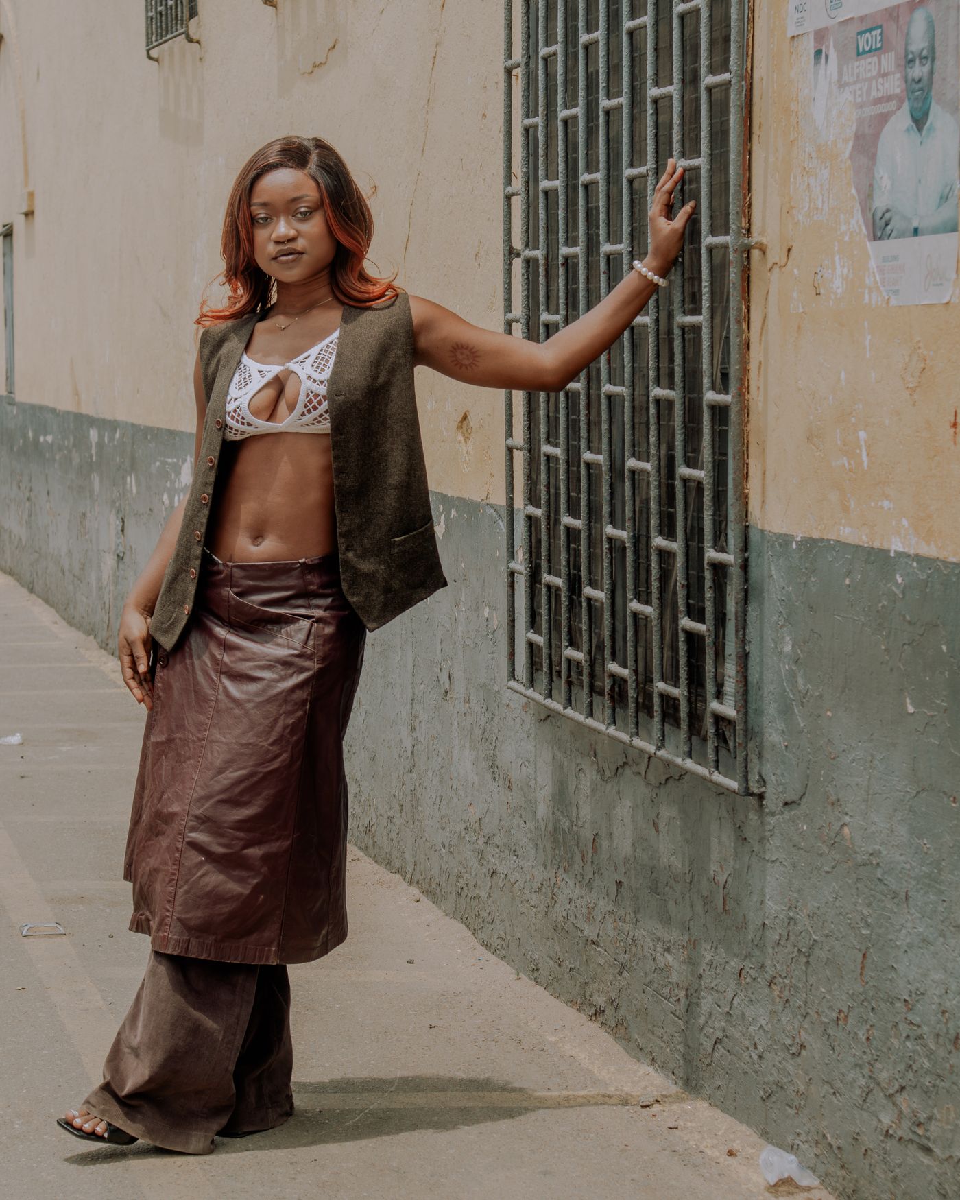 The vest worn open over brown trousers on a city street in Accra.