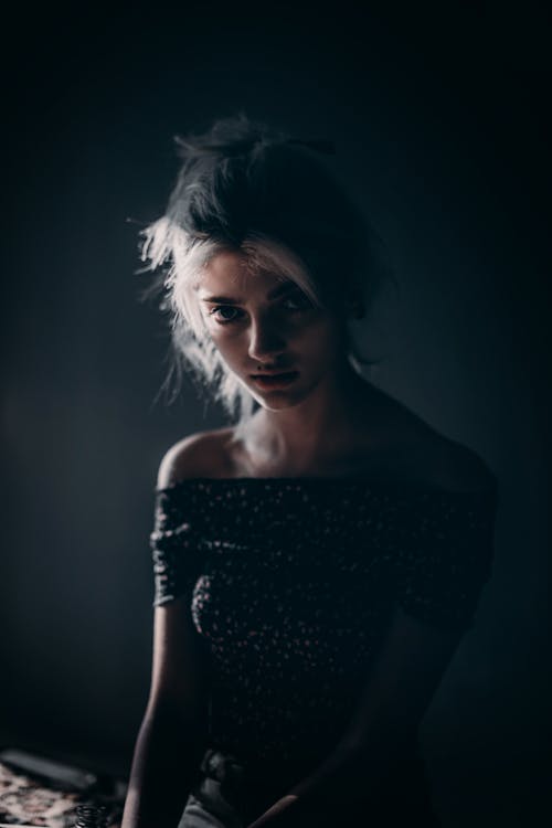 혼자 어두운 방에 앉아있는 여자의 사진