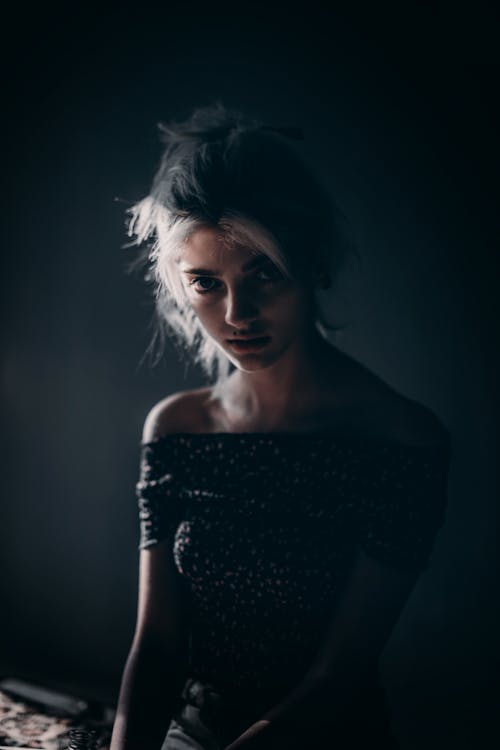 Photo of Woman Sitting in a Dark Room Alone Posing