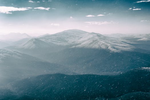 Scenery of dark and gloomy sky above snowy mountain valley with snow falling down