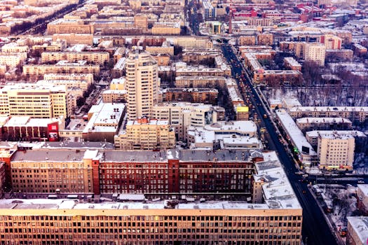 Explore a vibrant cityscape with snow-dusted rooftops and bustling streets from above.