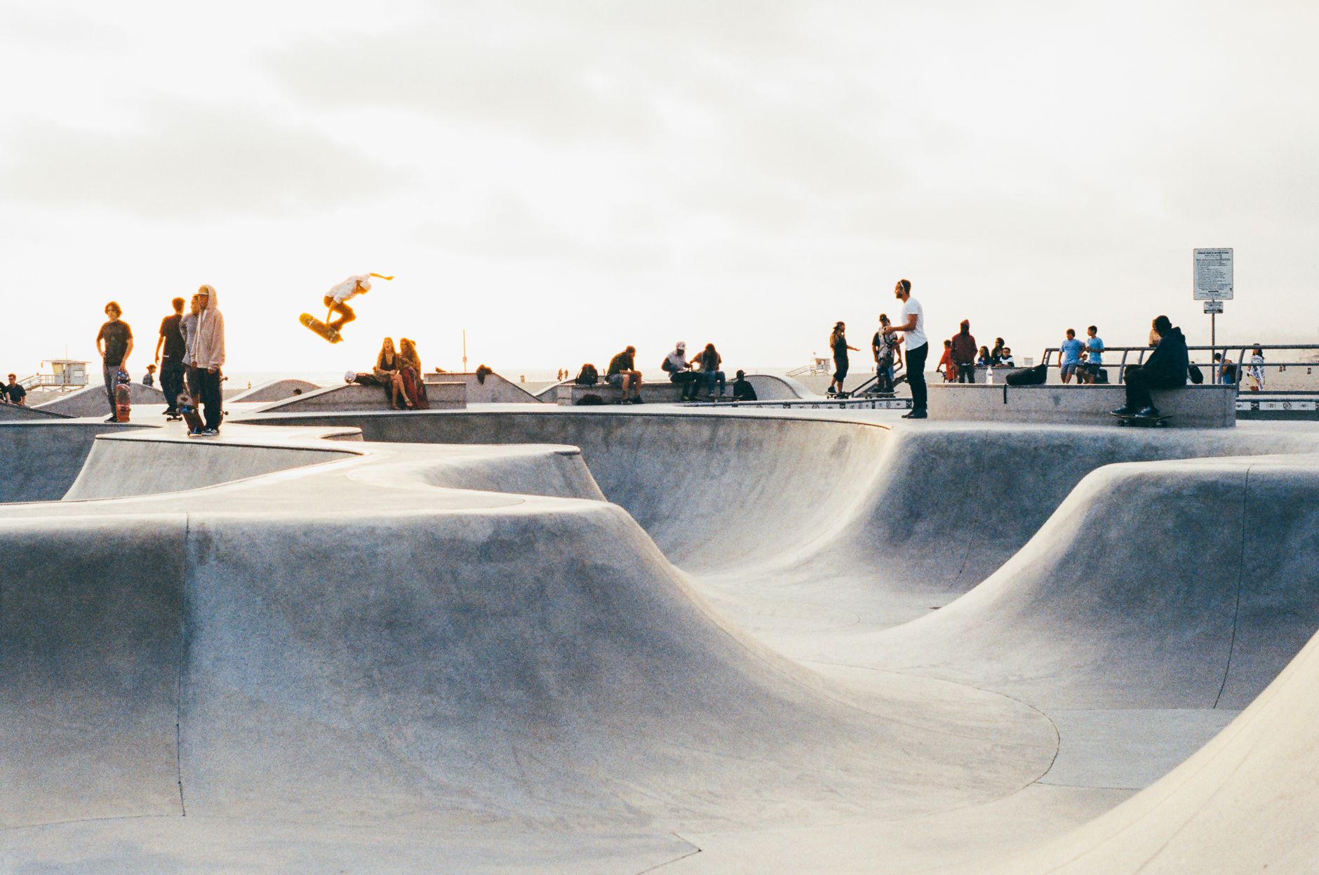 Houston skateboarder practicing a bowl carve under late afternoon light, with concrete coping and punk poster nearby
