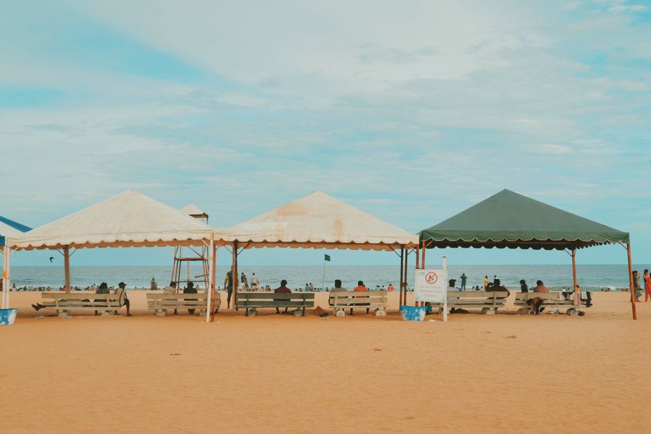 A tranquil beach scene with tents and benches, perfect for a relaxing day by the sea.